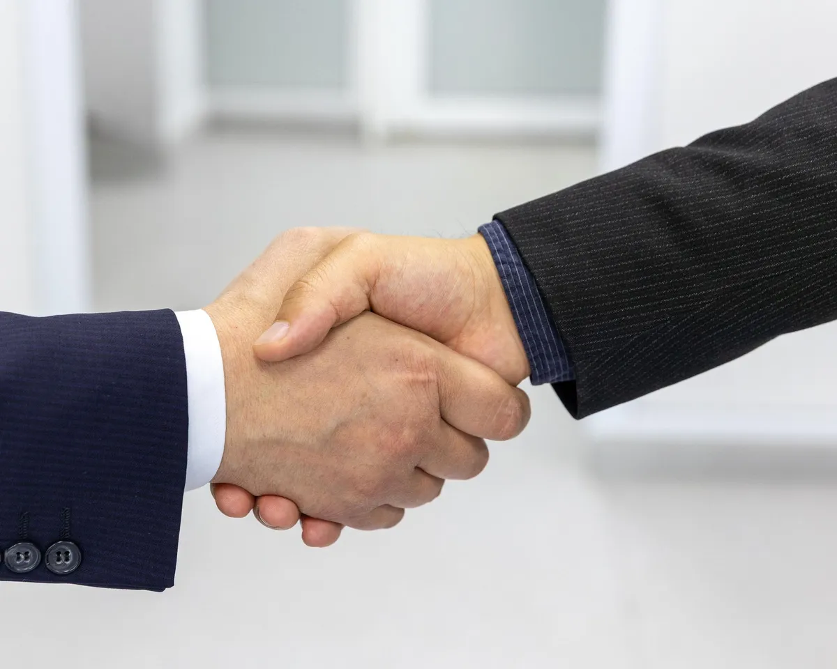 Dos personas se dan la mano en una oficina clara.